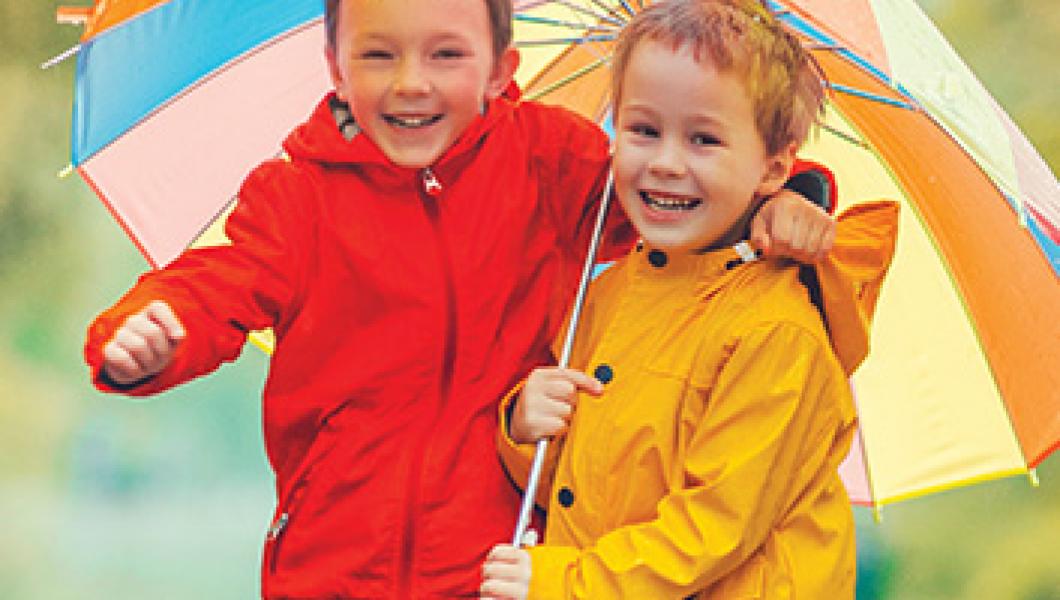 two young boys smiling under umbrella