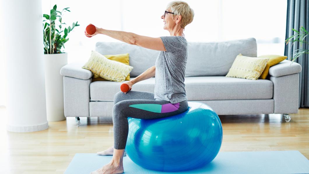 woman exercising in living room with weights and yoga ball