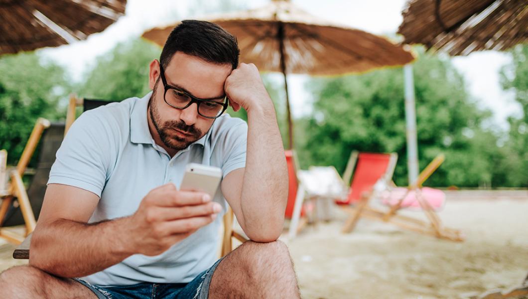 Man looks at cell phone while on vacation