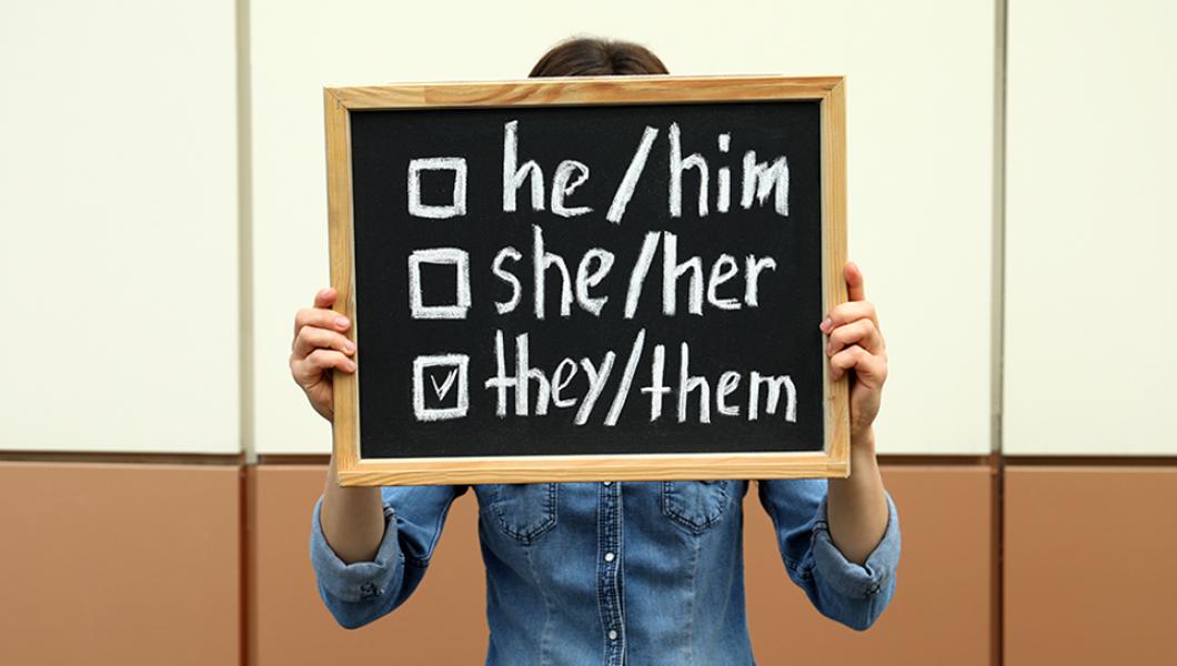 Person holding sign with pronoun choices