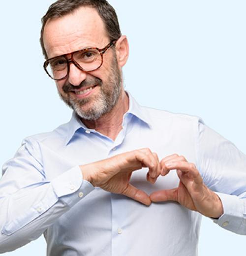 smiling man making heart with hands over chest