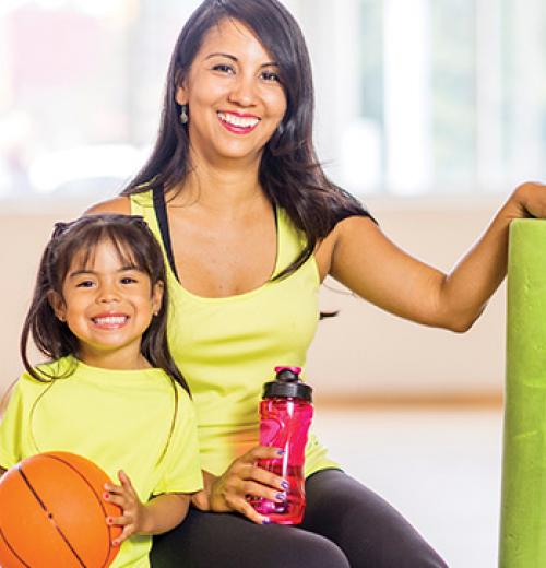 mother and daughter smiling with yoga mat and basketball