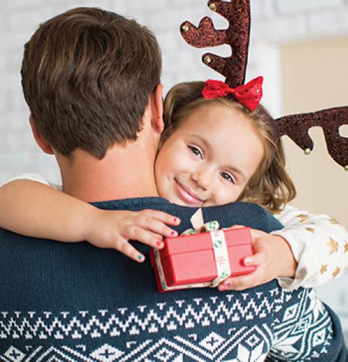 father holding smiling daughter with gift box