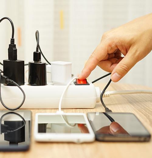 hand plugging in devices into power strip