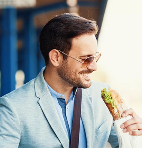 man eating a sandwich outside