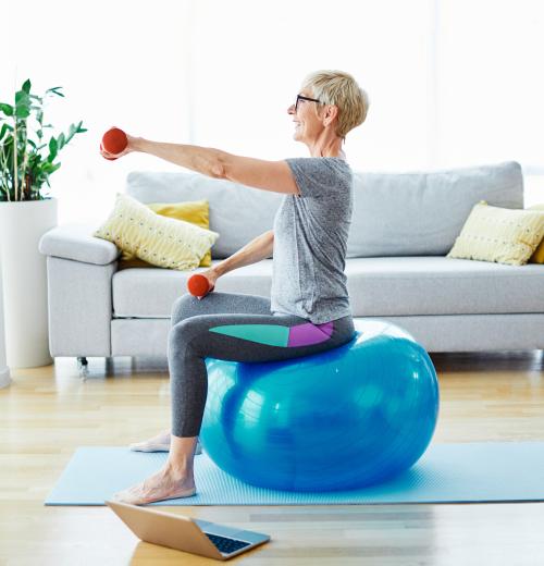 woman exercising in living room with weights and yoga ball