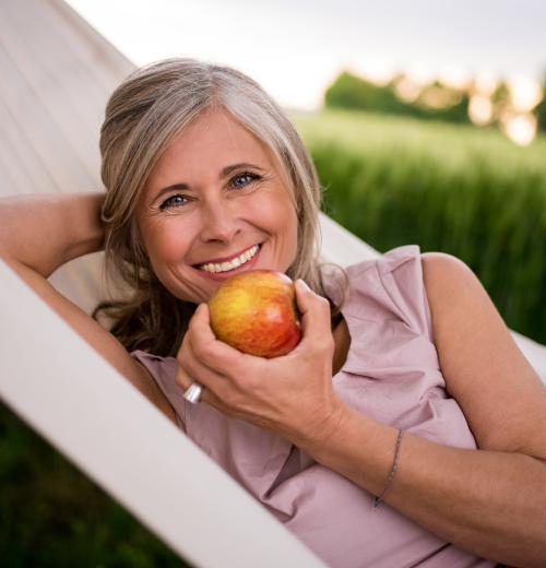 happy woman in hammock eating an apple