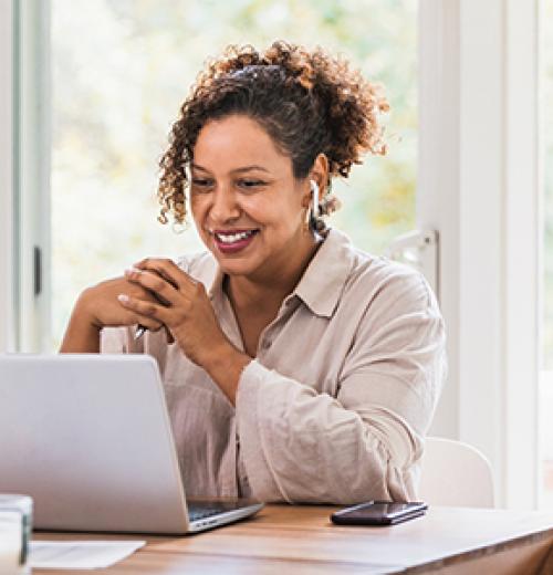 Woman smiling and taking health risk assessment on laptop