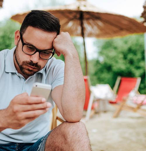 Man looks at cell phone while on vacation