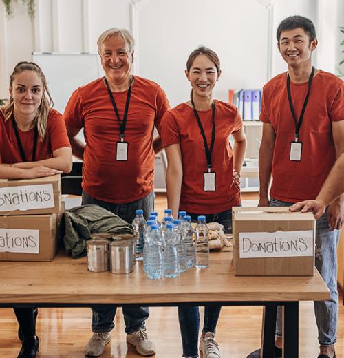Group of smiling volunteers around a table of donations