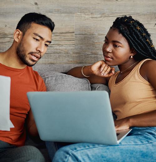 Young couple looking over paperwork on sofa