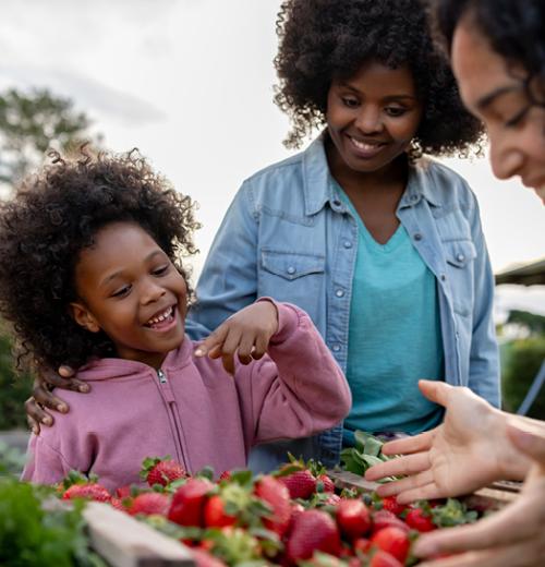 Mother and daughter choosing vegetables at farmer's market